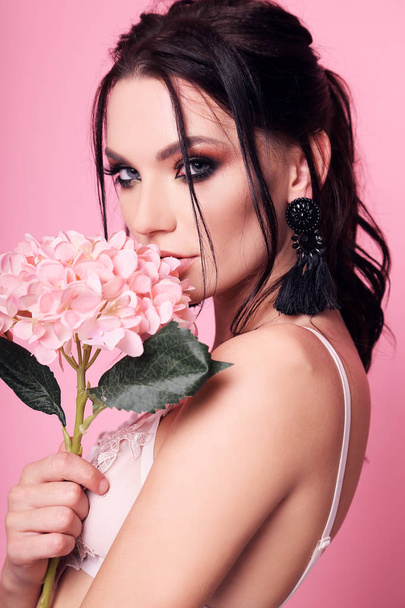 beautiful woman with dark hair and evening makeup with flowers - Fotó, kép