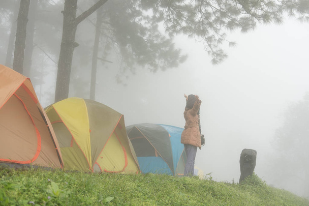 tourist raise hand with happiness near tent in mist & fog. campi - Zdjęcie, obraz