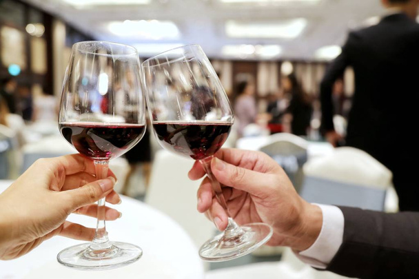 δύο πρόσωπα που τσούγκριζαν ποτήρια πλούσιο κόκκινο κρασί σε ένα πάρτι. Έννοια του να κάνει νέο φίλο, ενώνει Κόμματος, δεν οδηγώ ποτό - Φωτογραφία, εικόνα