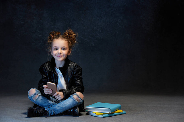 Little girl sitting with smartphone in studio - Foto, imagen