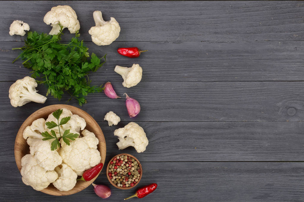 Fresh cauliflower with garlic and chili peppers on black wooden background with copy space for your text. Top view - Photo, Image