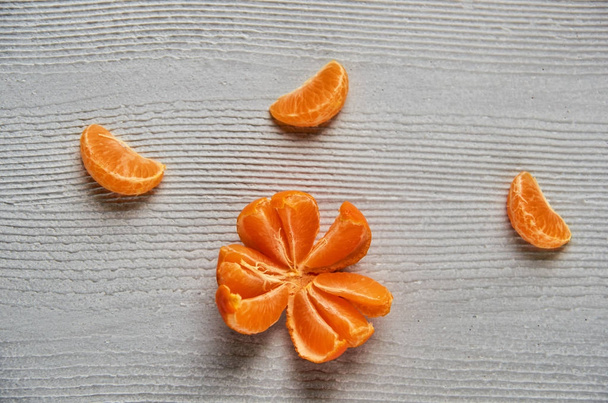 Tres rebanadas de naranja mandarina en el tablero de madera gris con espacio de copia gratuito. Mandarina fresca cruda naranja y mandarina amarilla pelada. Vista superior
 - Foto, imagen