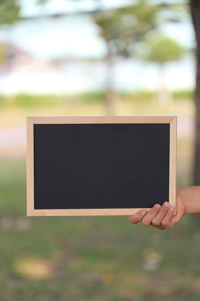 Mano de una mujer de negocios sosteniendo una imagen vacía de madera negra fr
 - Foto, imagen