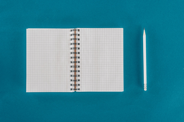 Top view of single pencil with blank notebook isolated on blue background - Foto, Imagem