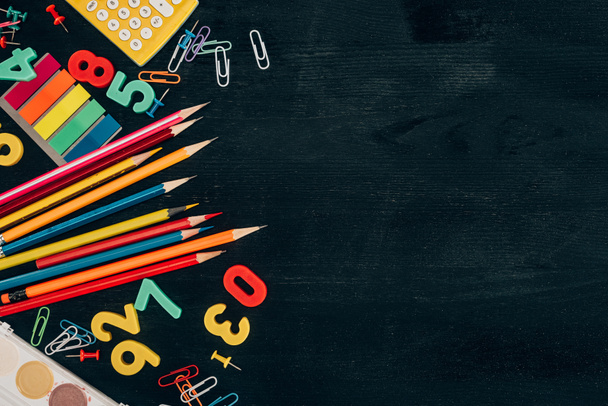Top view of composition of colorful school supplies isolated on dark board background - Photo, Image