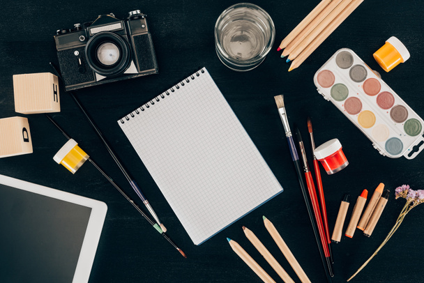 Top view of composition of colorful school supplies with blank notebook isolated on dark board background - Photo, Image