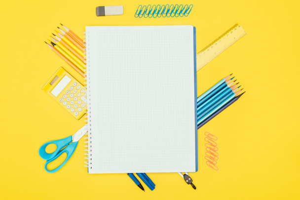 Vista superior de la composición de materiales escolares coloridos con cuaderno en blanco aislado sobre fondo amarillo
 - Foto, imagen