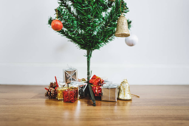 Різдвяна ялинка з різдвяними подарунками та прикрасами на дерев'яній підлозі, у вітальні
 - Фото, зображення