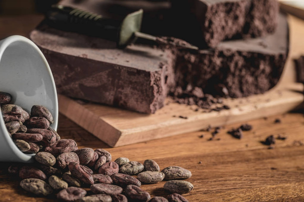 Sweet arrangement of cocoa beans and chocolate bars on wooden surface. - Foto, immagini