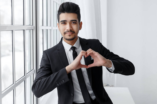 Νεαρός επιχειρηματίας στην αγάπη δείχνει σημάδι της καρδιάς - Φωτογραφία, εικόνα