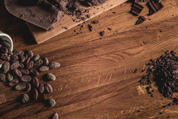 Sweet Table Top View arrangement of Cocoa beans, nibs and Chocolate bars on wooden surface. - Fotó, kép