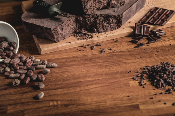 Sweet Table Top View arrangement of Cocoa beans, nibs and Chocolate bars on wooden surface. - Fotó, kép