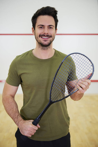 Portrét mužské squashové hráče s raketou na kurtu - Fotografie, Obrázek