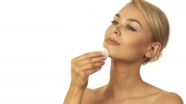 The well-groomed woman is wiping her face with a cotton pad - Imágenes, Vídeo