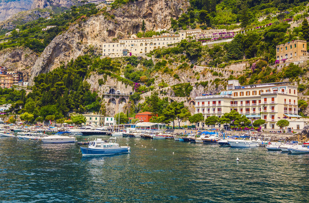 Puerto con barcos y yates de las casas de colores del pueblo de Amalfi, situado en la roca, costa de Amalfi, Sorrento, Italia
. - Foto, imagen