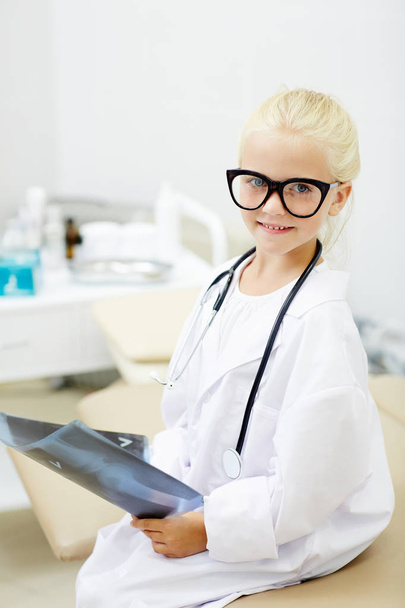 Pretty blond girl in whitecoat and eyeglasses holding x-ray image - Fotoğraf, Görsel