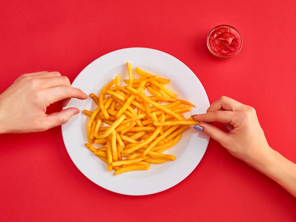 Young woman eating french fries potato with ketchup in a restaurant - Foto, Imagem
