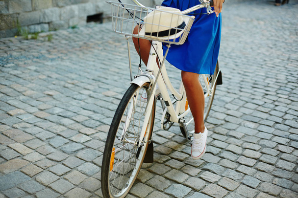 Low section of active girl in blue skirt riding bicycle - Photo, Image