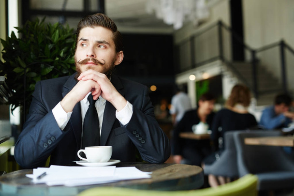 Homme d'affaires pensif assis dans un café par tasse de café à la pause
 - Photo, image