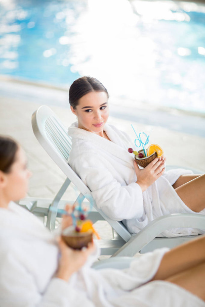 Spokojny dziewczyna w tropikalny koktajl rozmowy z przyjaciółką hotelu przy basenie - Zdjęcie, obraz