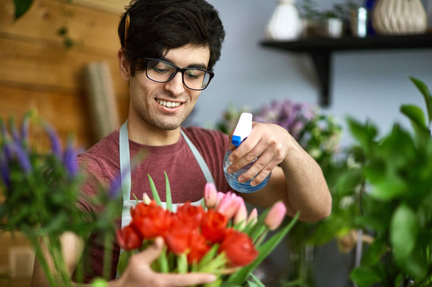 Felice giovane uomo con tulipani irrigatori
 - Foto, immagini