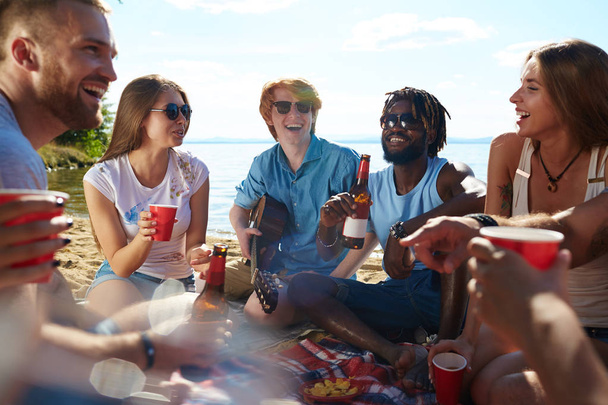 Cirkel van gelukkige jonge mensen met drankjes genieten van strand partij - Foto, afbeelding