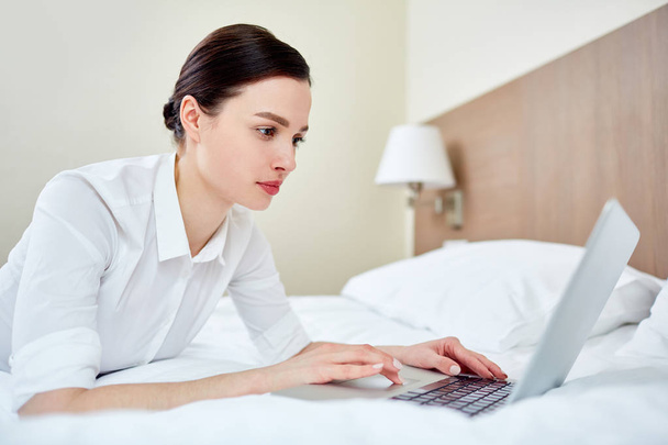 Busy female lying on bed and networking - Photo, Image