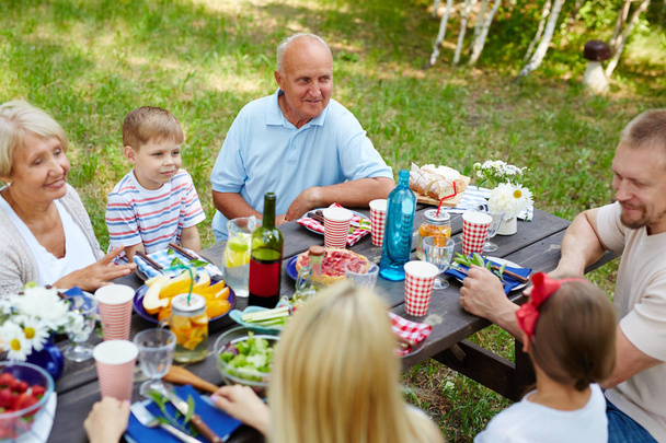 Grande famille amicale ayant dîner en plein air le jour d'été
 - Photo, image