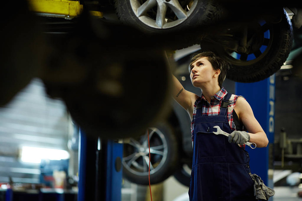 Female technician with wrench repairing car - Foto, Bild