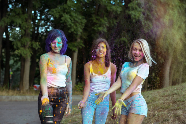 Three attractive women with tossing up orange and yellow Holi po - Photo, Image