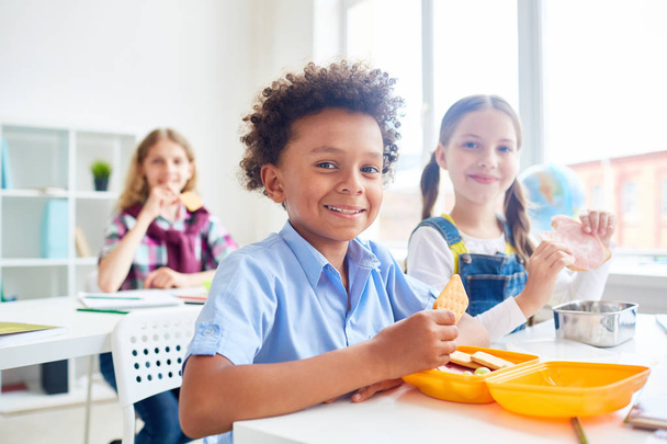 Giovani carini con cracker e sandwich che mangiano il pranzo dal contenitore a pausa tra le lezioni
 - Foto, immagini