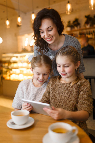Woman and little girls with touchpad enjoying leisure in cafe - Foto, Bild