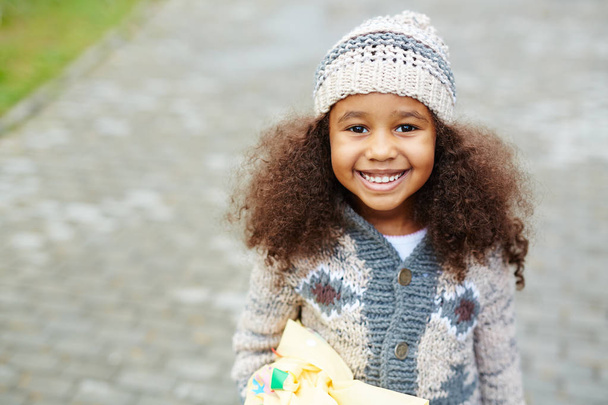 Portret Ładna dziewczyna African-American patrząc na kamery i uśmiechał się, noszenie dzianiny kapelusz i sweter w ciepły, jesienny dzień - Zdjęcie, obraz
