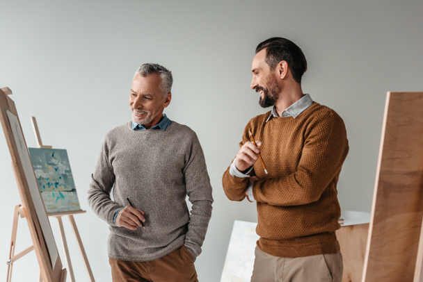 smiling male senior artists standing together in art studio - Valokuva, kuva