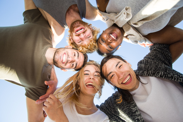 Cheerful friends huddling against blue sky on sunny day - Photo, Image