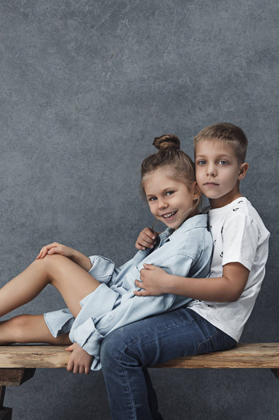 Kis lány és egy fiú, a szürke háttér portréja - Fotó, kép