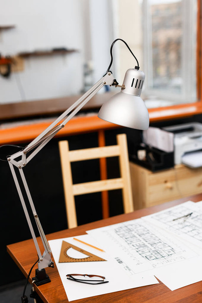 Lamp, measuring tool and sketch of construction on desk - Fotó, kép