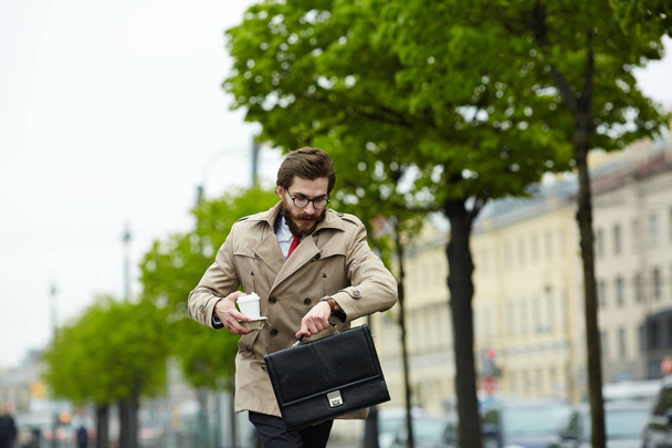 Homme d'affaires contemporain se déplaçant le long de la rue et regardant la montre
 - Photo, image