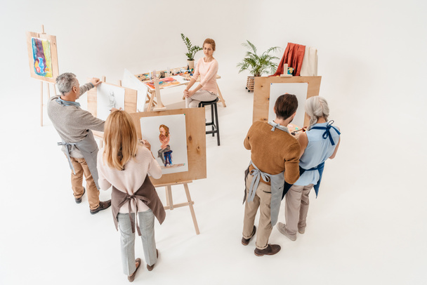 high angle view of senior people painting on easels during art class - Photo, Image