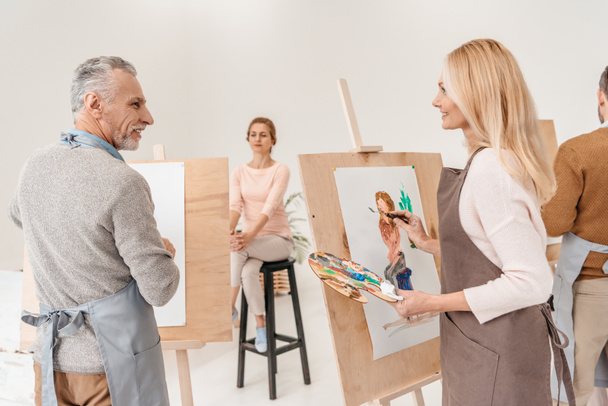 старшие художники рисуют и смотрят друг на друга в художественной студии
 - Фото, изображение