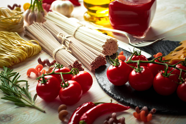 Pasta in a composition with vegetables and kitchen accessories on an old background - Photo, Image