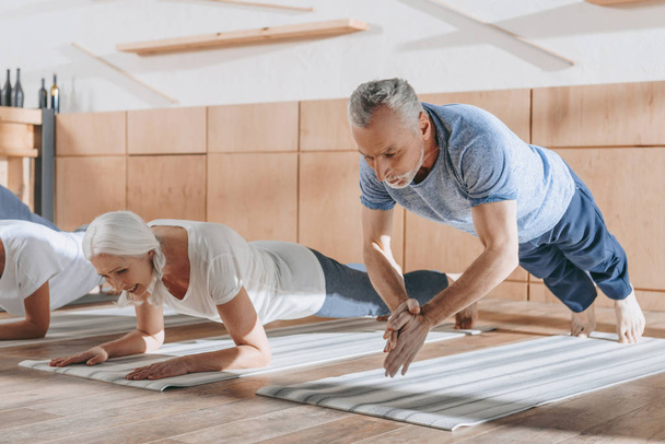 group of senior people doing plank on yoga mats in studio - Фото, зображення