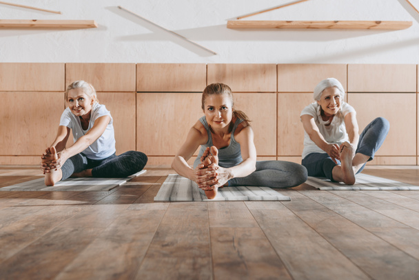 Frauengruppe dehnt sich im Studio auf Yogamatten - Foto, Bild
