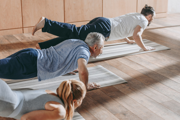 group of people practicing yoga on mats in studio - Foto, Imagem