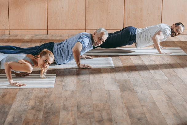 instructeur féminin faisant de l'exercice avec des hommes matures sur des tapis de yoga lors de cours de formation
  - Photo, image