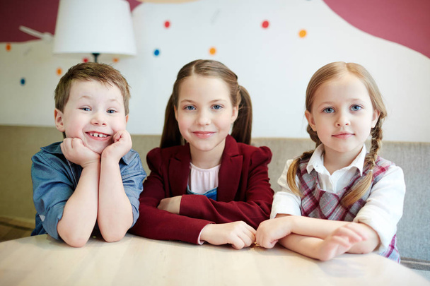 Group of little friends sitting by table in cafe - Фото, зображення