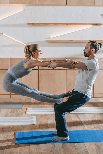 middle aged couple practicing yoga together in fitness studio - Foto, imagen
