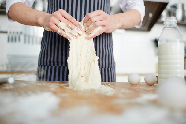 Chef-kok handen kneden deeg op werkplek - Foto, afbeelding