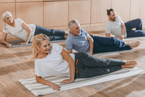 Lächelnde Senioren beim Training auf Yogamatten - Foto, Bild