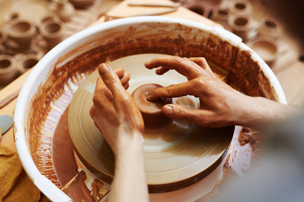 Pottery machine rotating while artisan making jugs - Foto, imagen